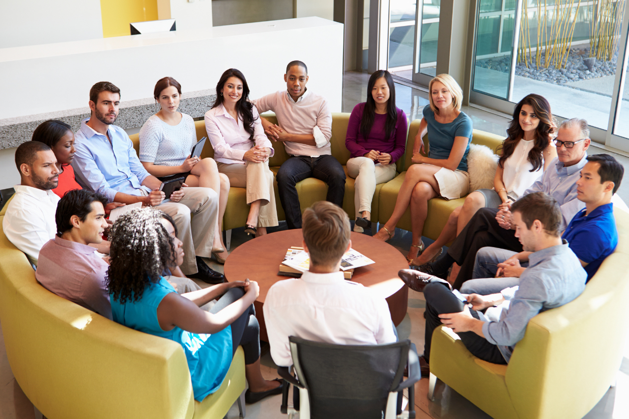 Group of staff sitting in a circle listening to a company update