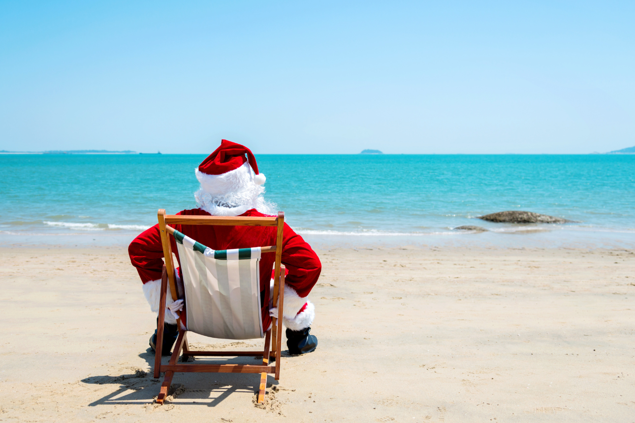 Website blog post 1280×853 Santa Claus sitting on a beach in the sunshine