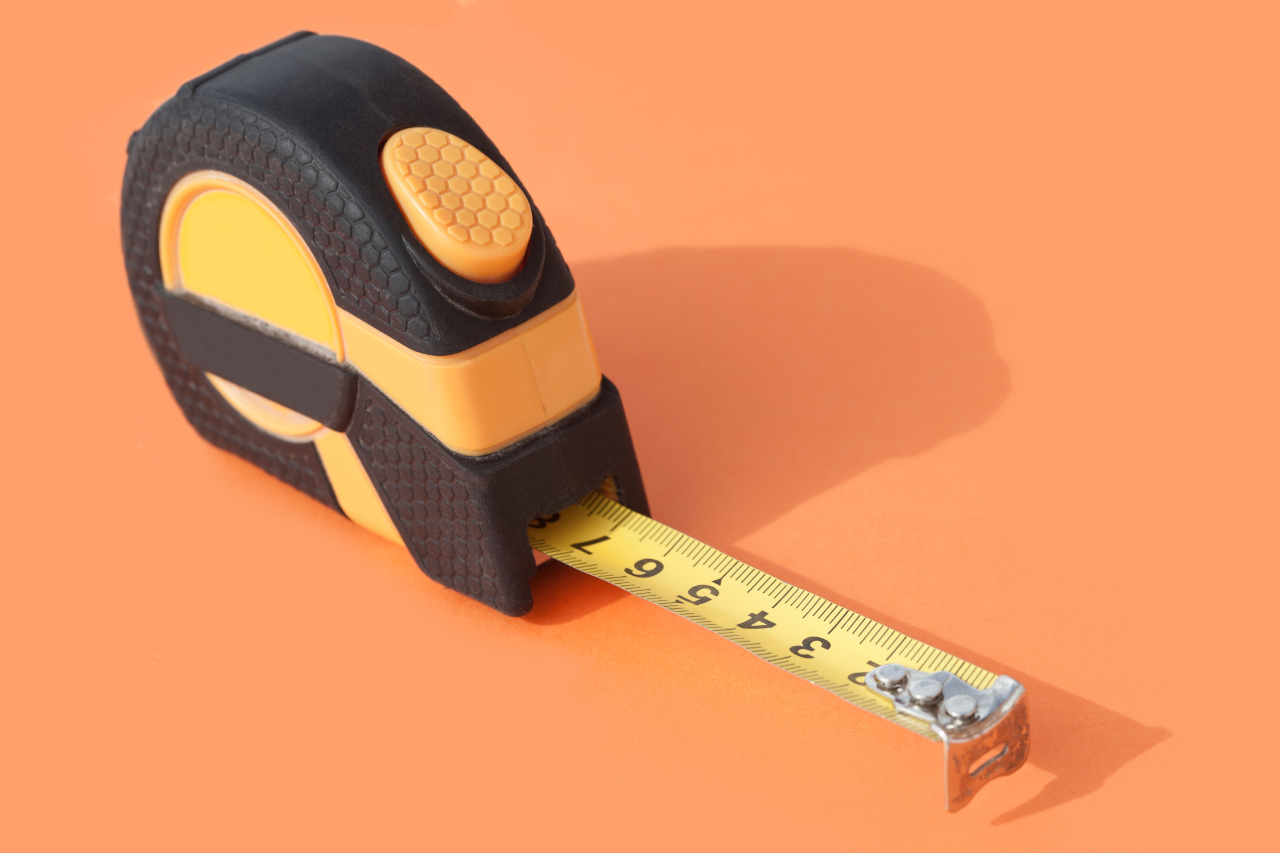 Tape measure Photo of a tape measure on an orange background with yellow measure tape pulled out ready to measure something